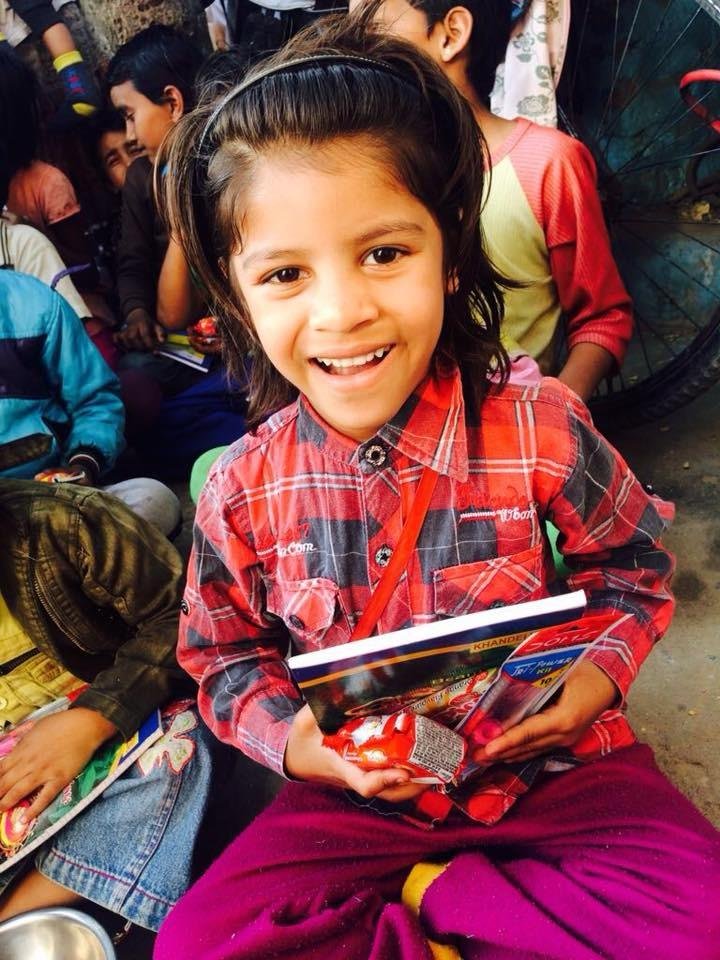 Aangan – smiling girl child with notebook, VAEWS education